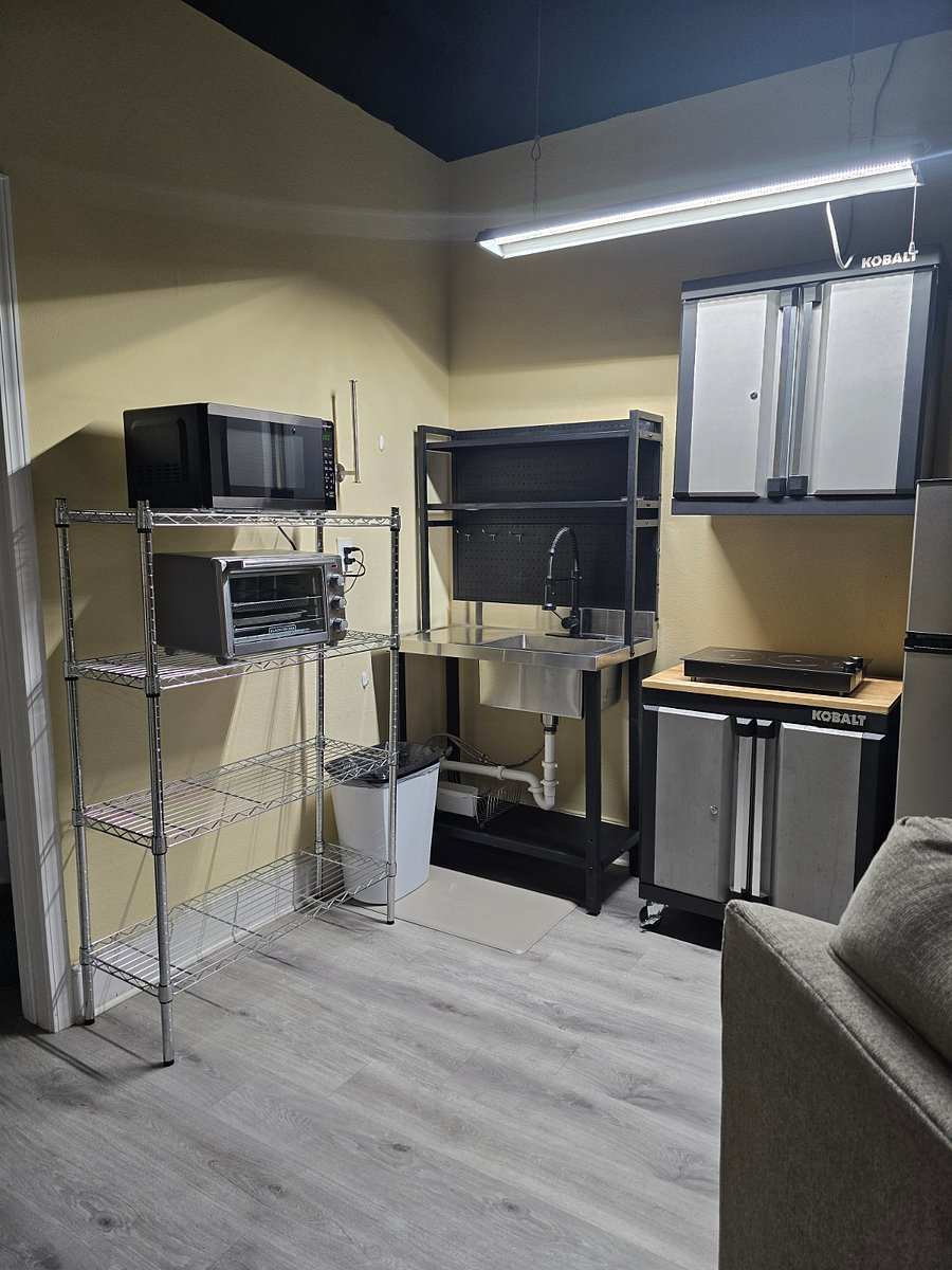 Studio 105 kitchenette: a microwave and toaster oven on wire shelving, a sink and tool-chest cabinets.